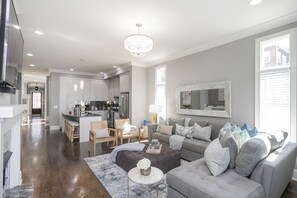 Un soggiorno moderno con un divano grigio, un tavolino da caffè e un lampadario.