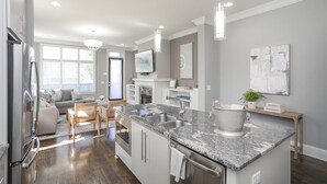 A modern kitchen with granite countertops, stainless steel appliances, and pendant lighting.