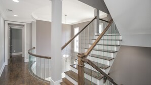 A modern staircase with glass railings and wooden steps, leading to an upper floor.