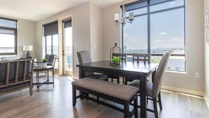 A dining area with a dark wooden table, cushioned chairs, and a chandelier.