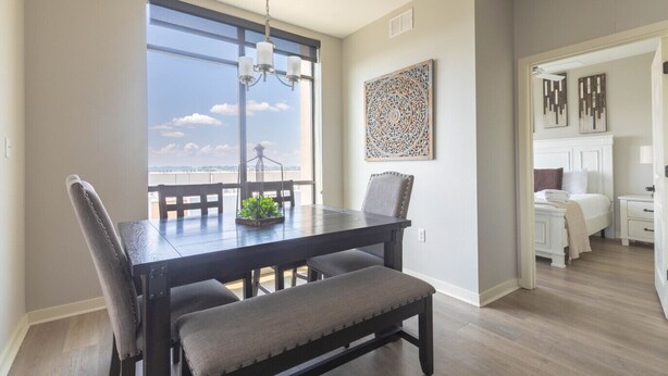 A dining area with a large window, a chandelier, and a decorative wall piece.