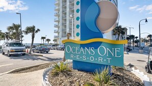 Oceans One Resort -hotellin moderni kyltti, joka sijaitsee vilkkaan kadun varrella. Taustalla näkyy palmuja ja korkea rakennus.