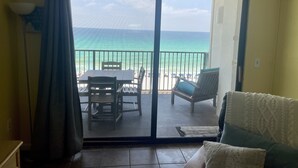 Quarto com porta de vidro deslizante que dá para uma varanda com vista para a praia e oceano.