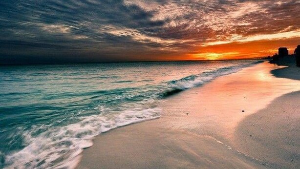 Uma praia com ondas e um pôr do sol.