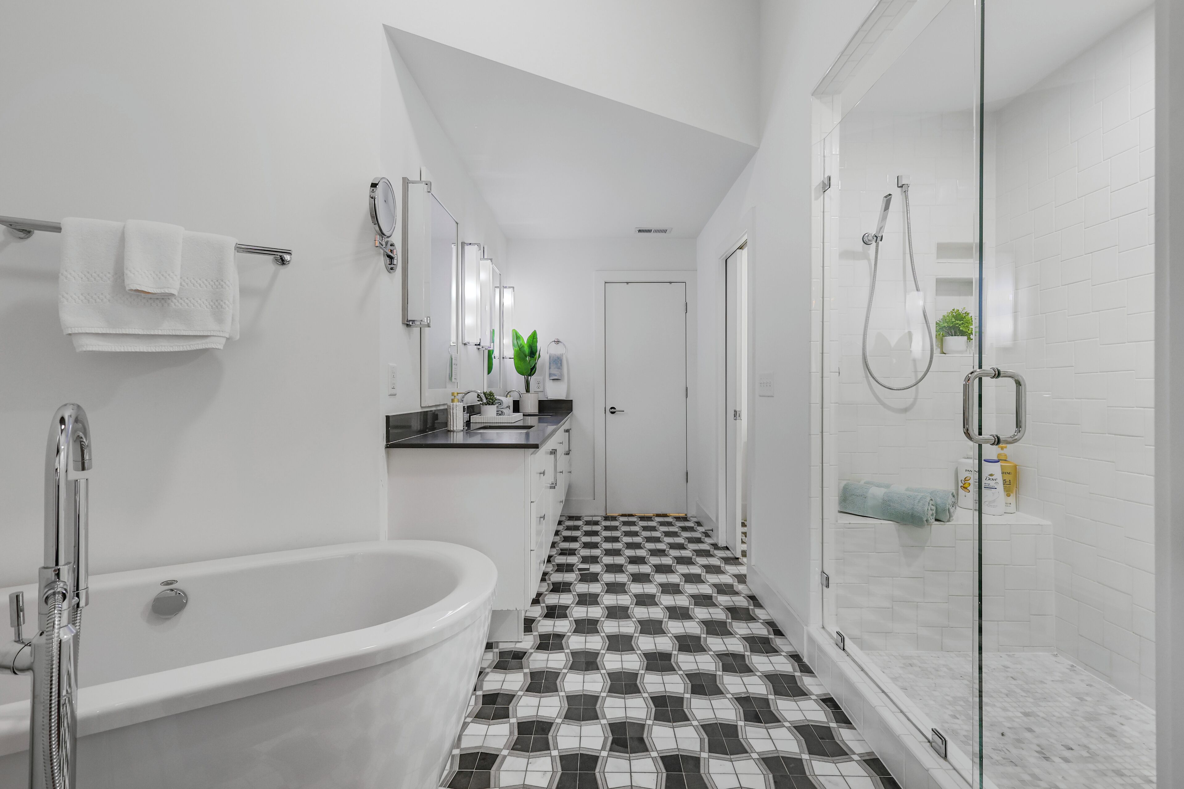 Une salle de bain moderne avec une baignoire sur pieds, une douche à parois de verre et un carrelage au motif à carreaux.