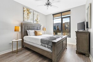 Une chambre à coucher avec un lit, des lampes de chevet, un ventilateur de plafond, une fenêtre donnant sur un beau paysage et un téléviseur posé sur un meuble.