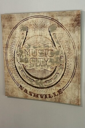 Une enseigne de style rétro avec les mots « MUSIC CITY » et « NASHVILLE » sur un fond circulaire agrémenté d’éléments décoratifs.