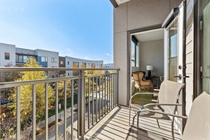 Un balcon donnant sur les immeubles voisins, avec une chaise et une table.