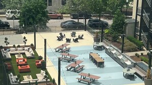 Un área de patio al aire libre con asientos, mesas y un pequeño césped.
