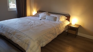 A neatly made bed with a patterned bedspread and pillows, two bedside tables with lamps, and a window with curtains. - 3 bed 2 bath home in heart of Silicon Valley (Redwood City)