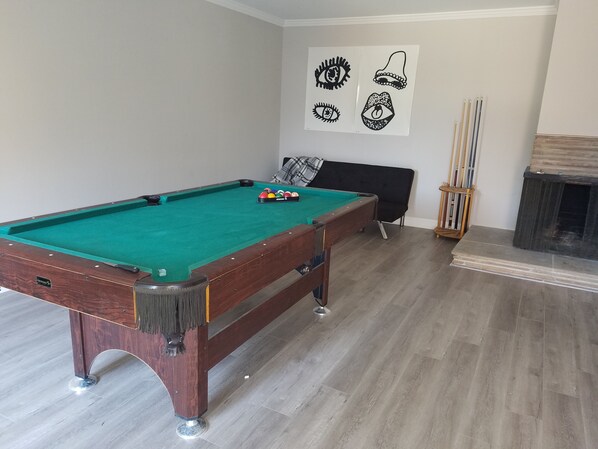 A pool table in a room with a sofa and a fireplace.