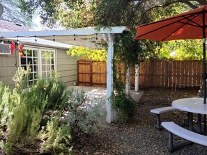 A patio area with a white pergola, a wooden fence, and a table with benches.
