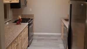 A kitchen with beige cabinets, a stainless steel refrigerator, a microwave, and a gas stove. - 3 bed 2 bath home in heart of Silicon Valley (Redwood City)