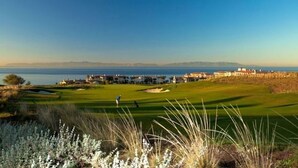 A golf course with a view of the ocean and a residential area in the background.