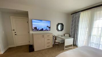 A hotel room with a bed, a desk, a television, a mirror, and a window with curtains.