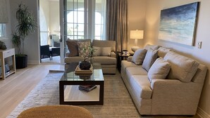 A modern living room with a sofa, a coffee table with a plant, and a painting on the wall.