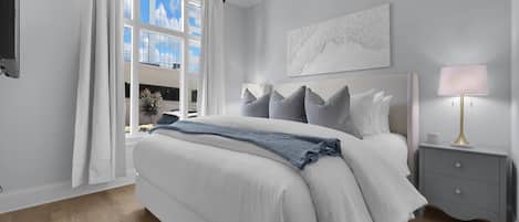 Un dormitorio moderno con una cama grande, una lámpara de noche, una mesita de noche y vistas al exterior a través de una ventana.