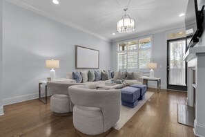 Un salon moderne avec un canapé d’angle, une table basse et un lustre.