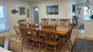 A dining area with a wooden table and chairs, a painting on the wall, and a chandelier. - Sleeps 15! DOWNTOWN LAKE GENEVA Fully Licensed for Weekend Rentals! (Lake Geneva)