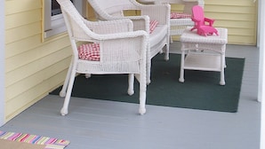 A porch with two white wicker chairs and a small table, a welcome sign, and a pair of flip-flops hanging on the wall. - Sleeps 15! DOWNTOWN LAKE GENEVA Fully Licensed for Weekend Rentals! (Lake Geneva)