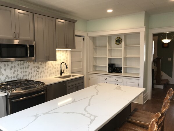 A modern kitchen with a large island, stainless steel appliances, and white cabinetry.