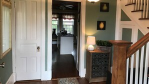 A hallway leading to a kitchen with a ceiling fan, a light fixture, and a staircase with wooden railings. - DOWNTOWN LAKE GENEVA 4 BR/4 BA House sleeps 15 (Lake Geneva)