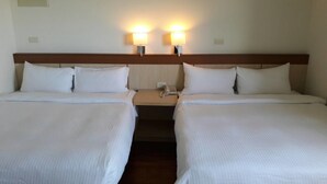 A hotel room with two single beds, a wooden headboard, bedside lamps, and a telephone on the nightstand.