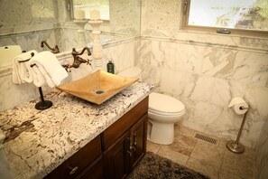 Un baño con un lavamanos de mármol, un inodoro blanco y una pared de mármol.