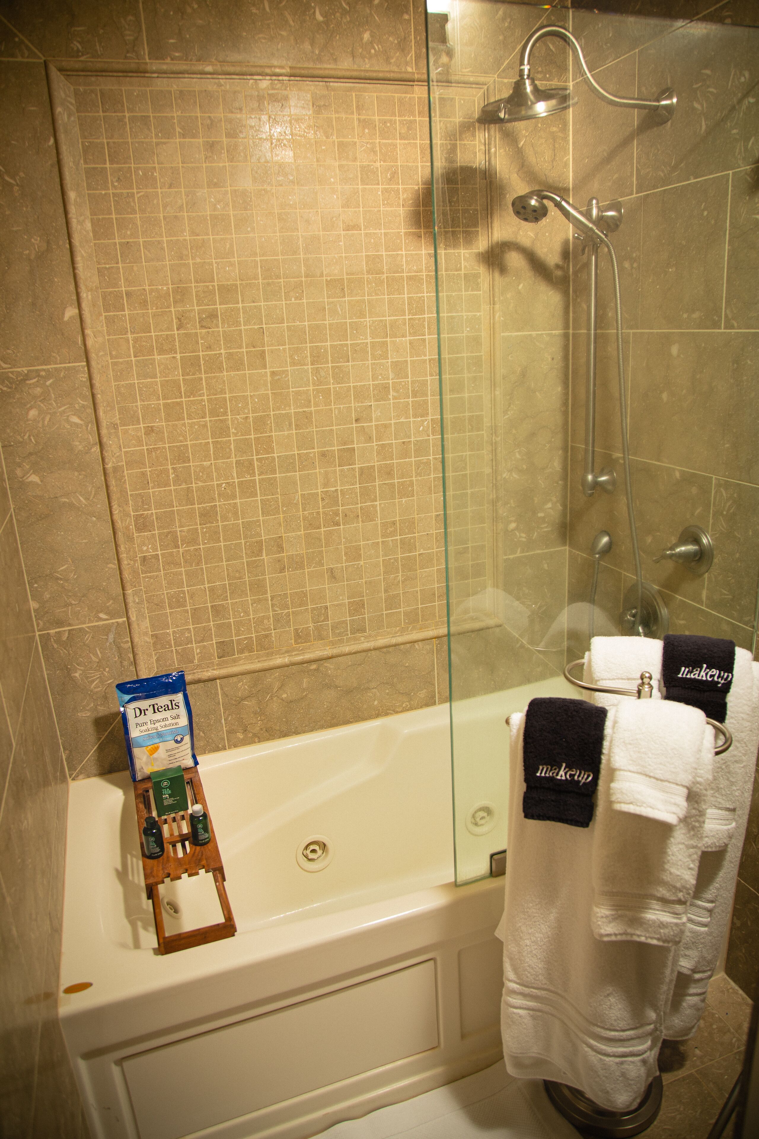 A bathroom with a glass-enclosed shower, a white bathtub, and two towels hanging on a rack.