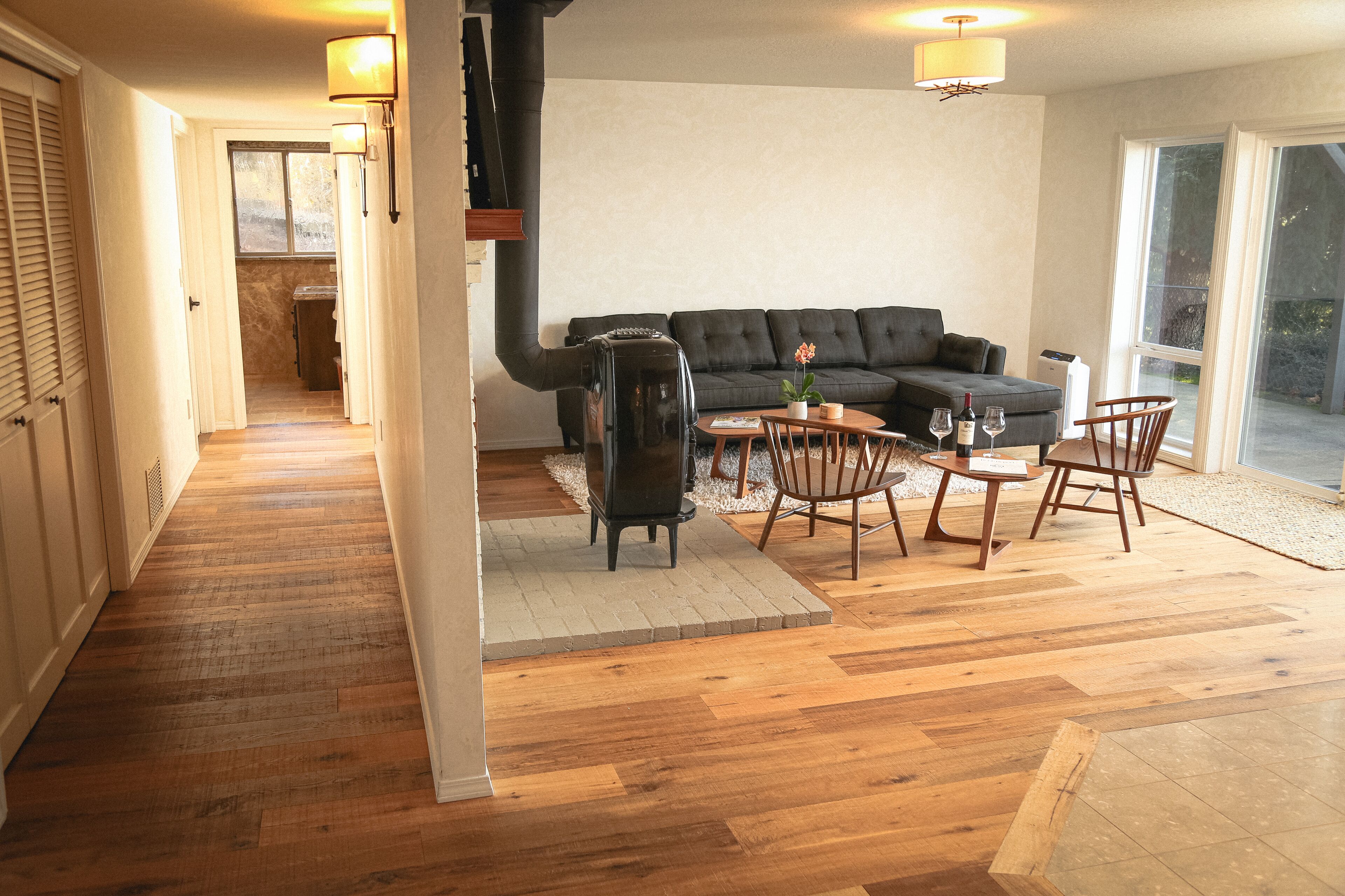 Een moderne woonkamer met een bank, eettafel, stoelen, een open haard en een groot raam.