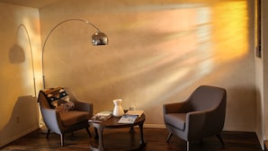 En moderne stue med to lænestole, et sofabord og en gulvlampe.