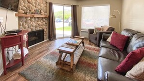 A living room with a stone wall, a fireplace, a leather sofa, and a coffee table.