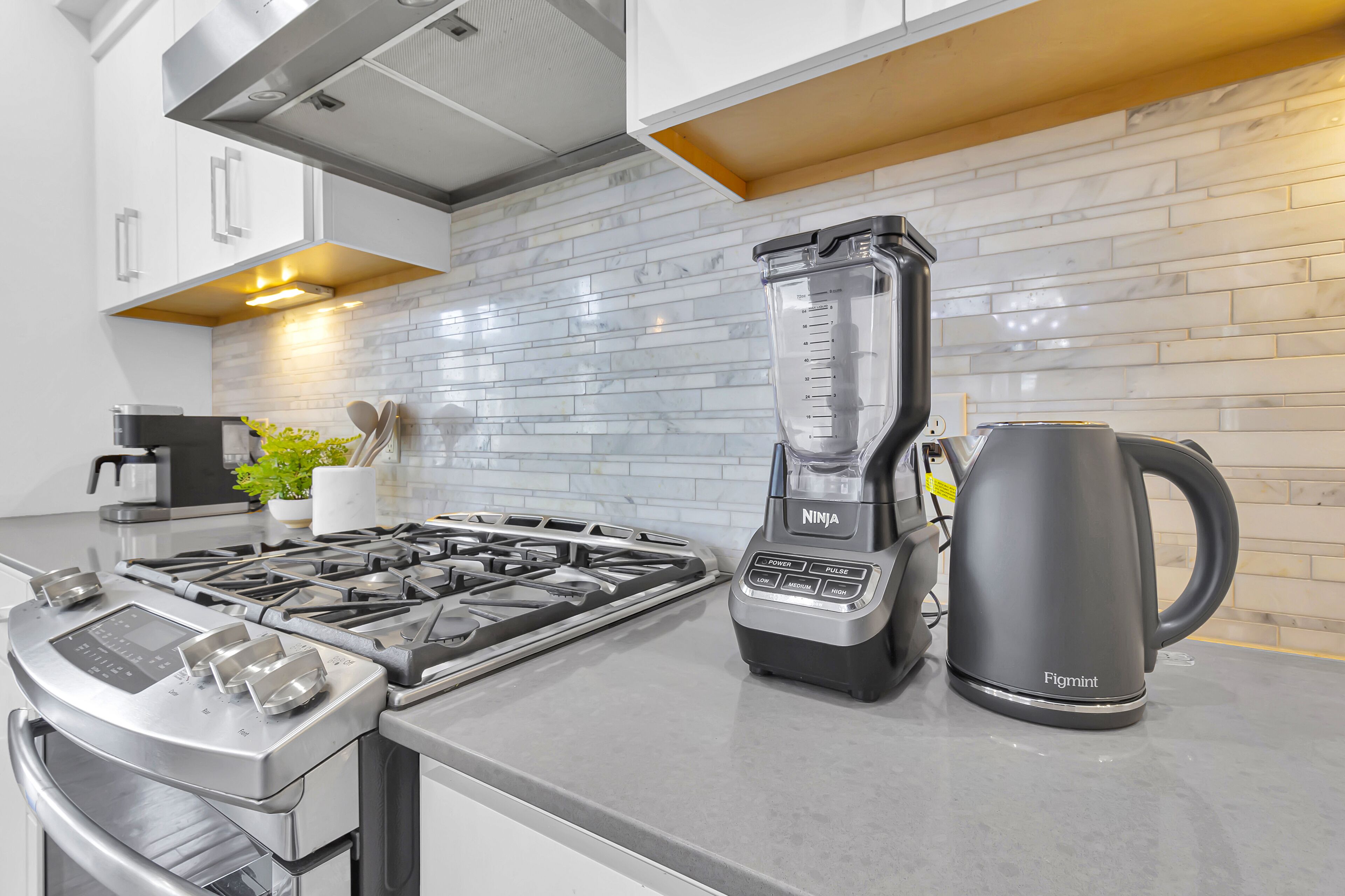 Una cocina moderna con estufa a gas integrada, licuadora y hervidor.