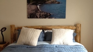 A bed with a wooden frame, blue bedding, and two pillows. - Keweenaw Vacation Rental - Great for families and groups- sleeps up to 7 (Ahmeek)