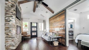 Une pièce spacieuse avec un mur en pierre, un plafond en bois, un canapé, une table et un lit.