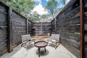 A wooden outdoor patio with two wicker chairs and a round table, surrounded by a rustic wooden fence. - Hideaway in Fredericksburg w/ Hot Tub + Fireplace (Fredericksburg)