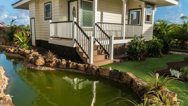 Ein zweistöckiges Haus mit Veranda und einem kleinen Teich.