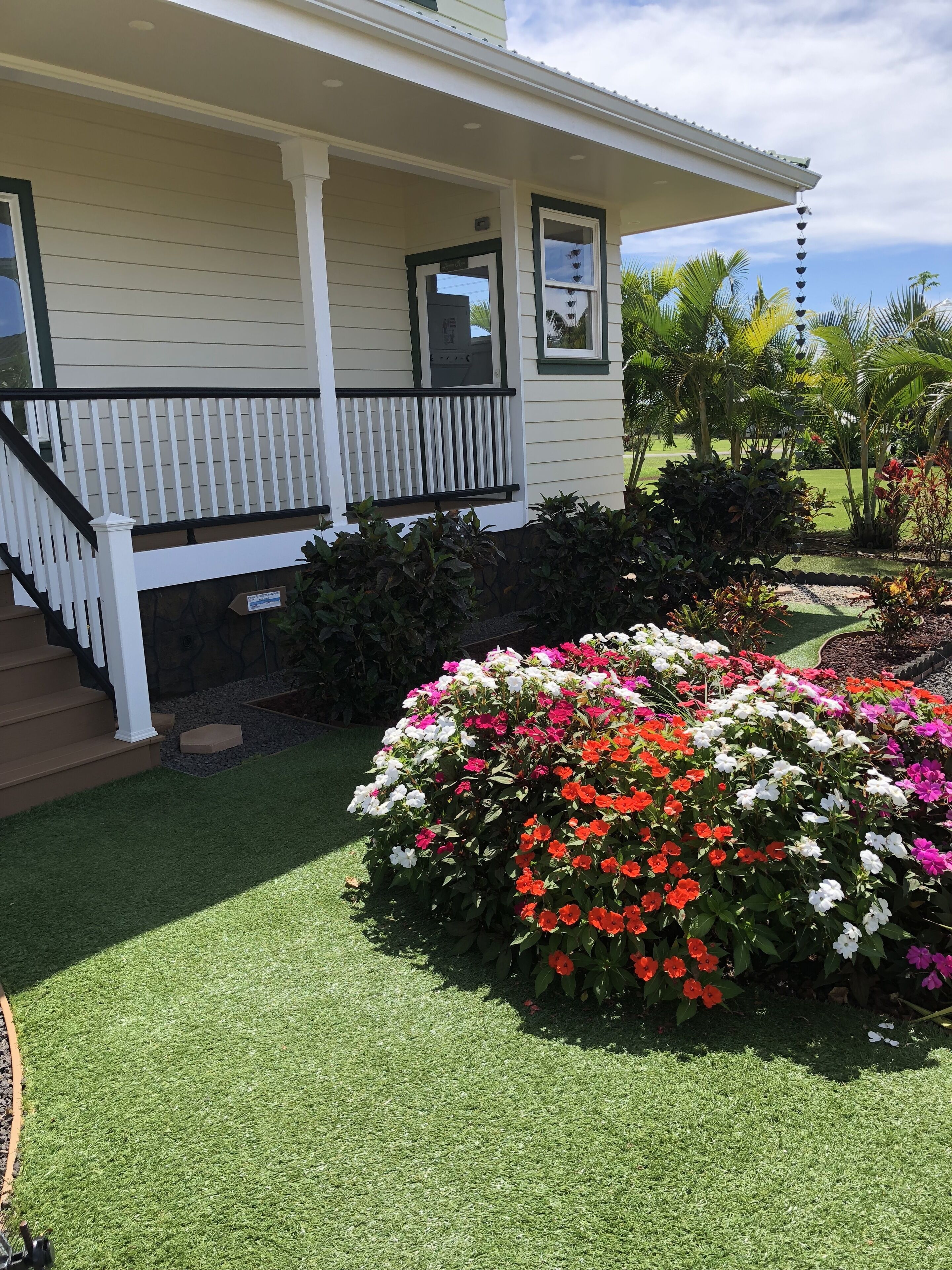 Una casa con porche, escalones y un jardín lleno de flores de colores.