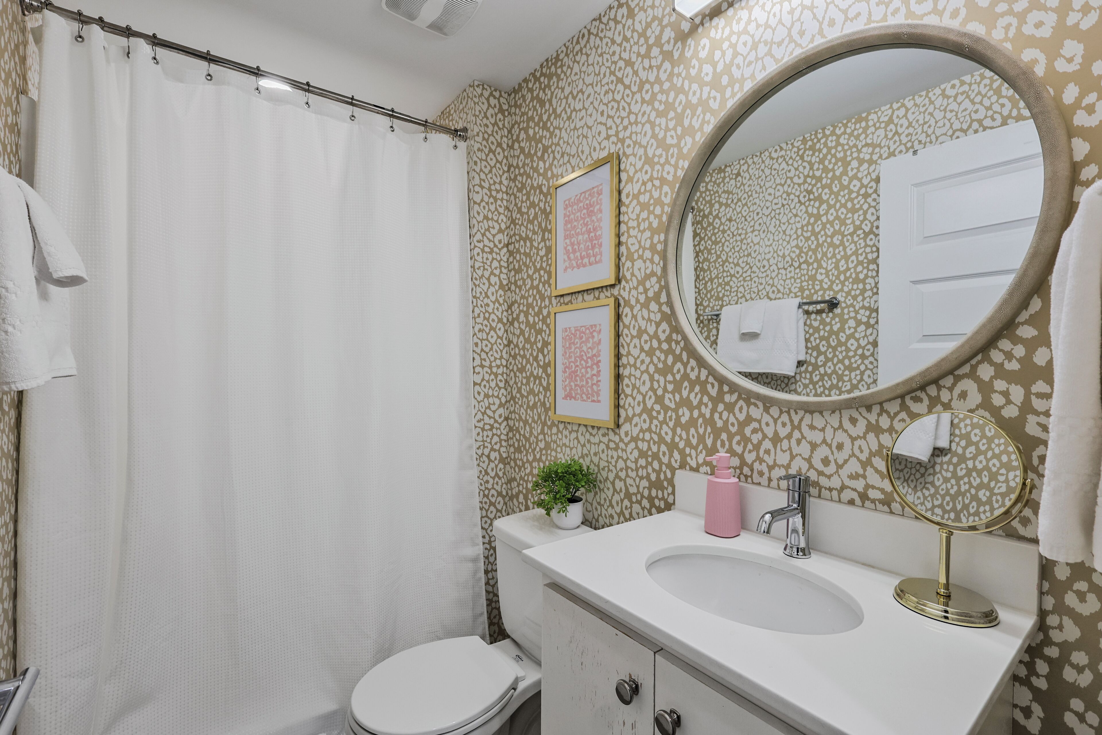 Een badkamer met douchegordijn, toilet, wastafel en spiegel.