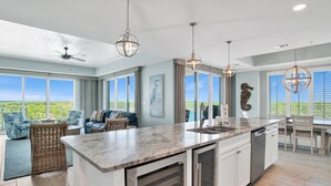 Una cocina amplia con una isla grande, lámparas colgantes modernas y vistas al exterior.