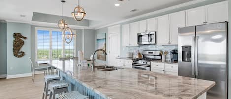 A spacious kitchen with a large island, stainless steel appliances, and pendant lighting.