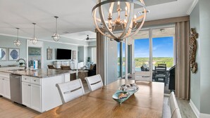 Una cocina amplia con una isla central, un comedor con una mesa grande y vistas al exterior a través de puertas correderas grandes.