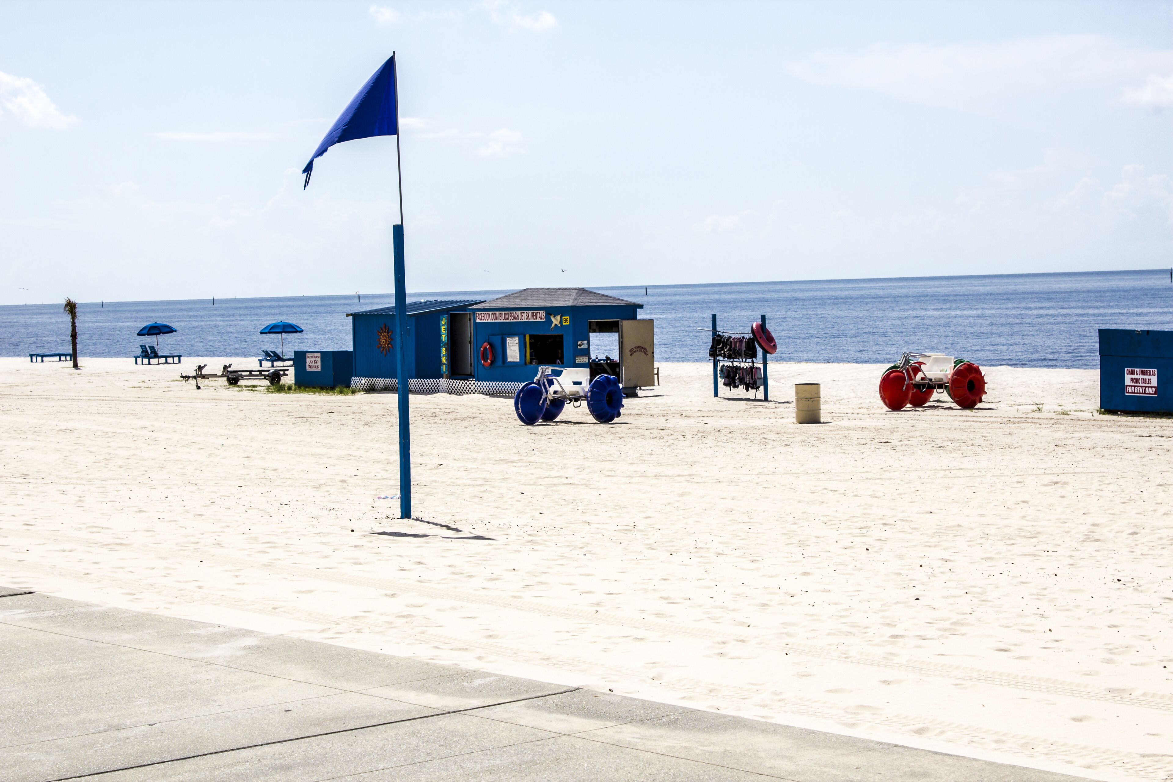 A beach with a lifeguard station, beach chairs, umbrellas, and a lifeguard tower.