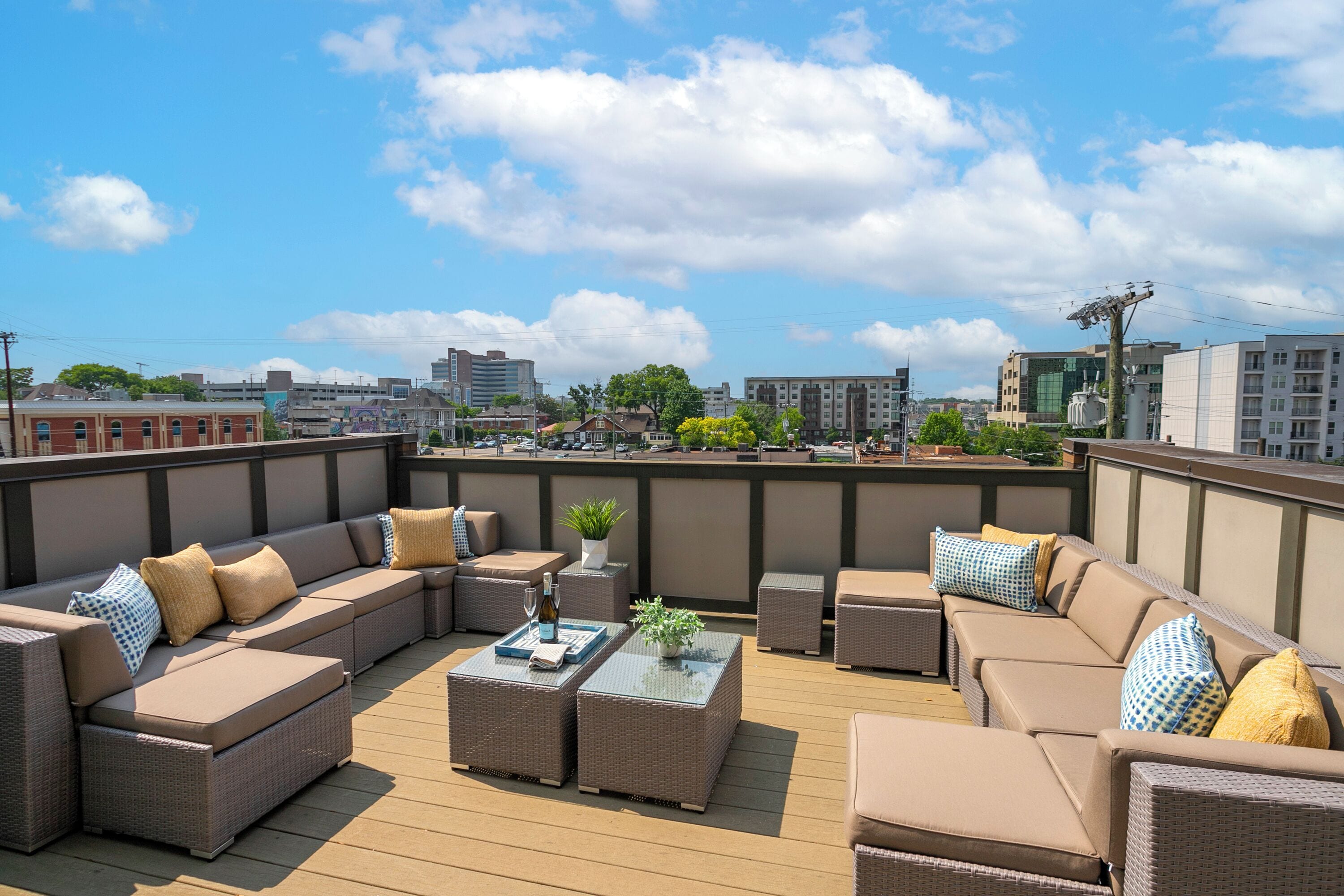 A rooftop deck with wicker furniture, a small table, and a potted plant.