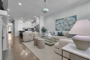 A modern living room with a sofa, ottomans, and a coffee table.