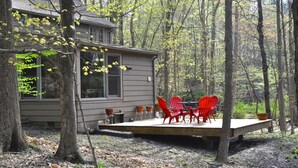 Une cabane dotée d’une terrasse, entourée d’arbres.
