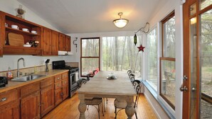 Une cuisine avec des meubles de rangement en bois, une cuisinière et une table à manger avec des chaises.