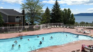 A swimming pool with people in it, surrounded by lounge chairs and a view of a lake. - Lake View Condo 871 # 4 with amazing views (Garden City)