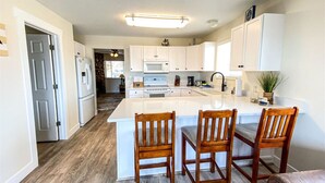 A modern kitchen with white cabinets, a central island with bar stools, and a wood floor. - Lake View Condo 871 # 4 with amazing views (Garden City)