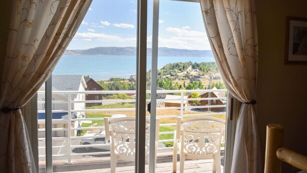 A balcony with white chairs and a view of a lake and houses. - Lake View Condo 871 # 4 with amazing views (Garden City)
